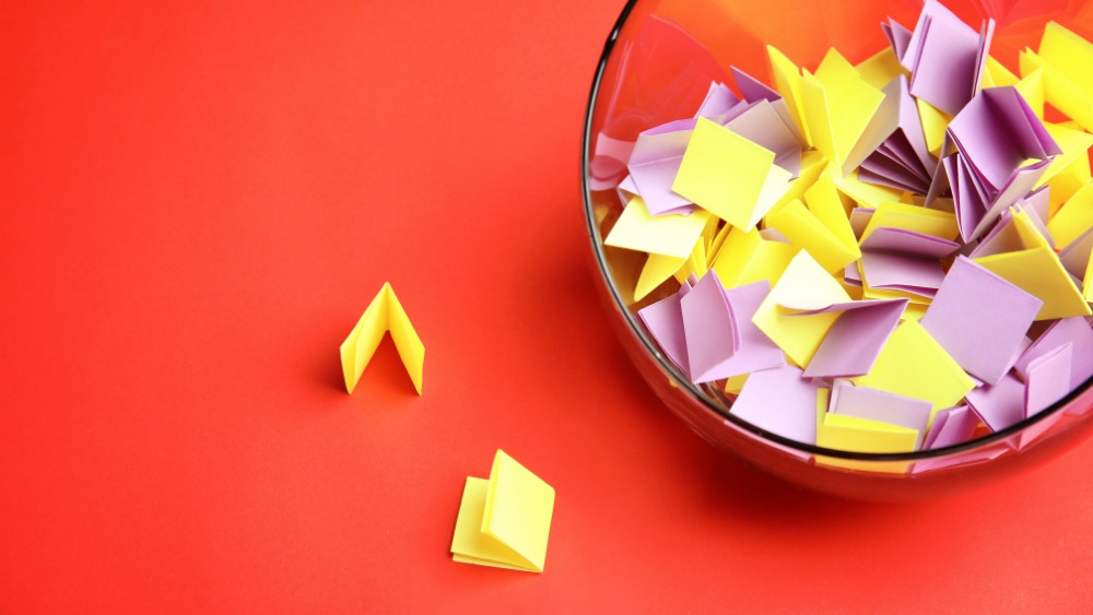 Folded paper raffle tickets spilling from a glass bowl, ready for a draw