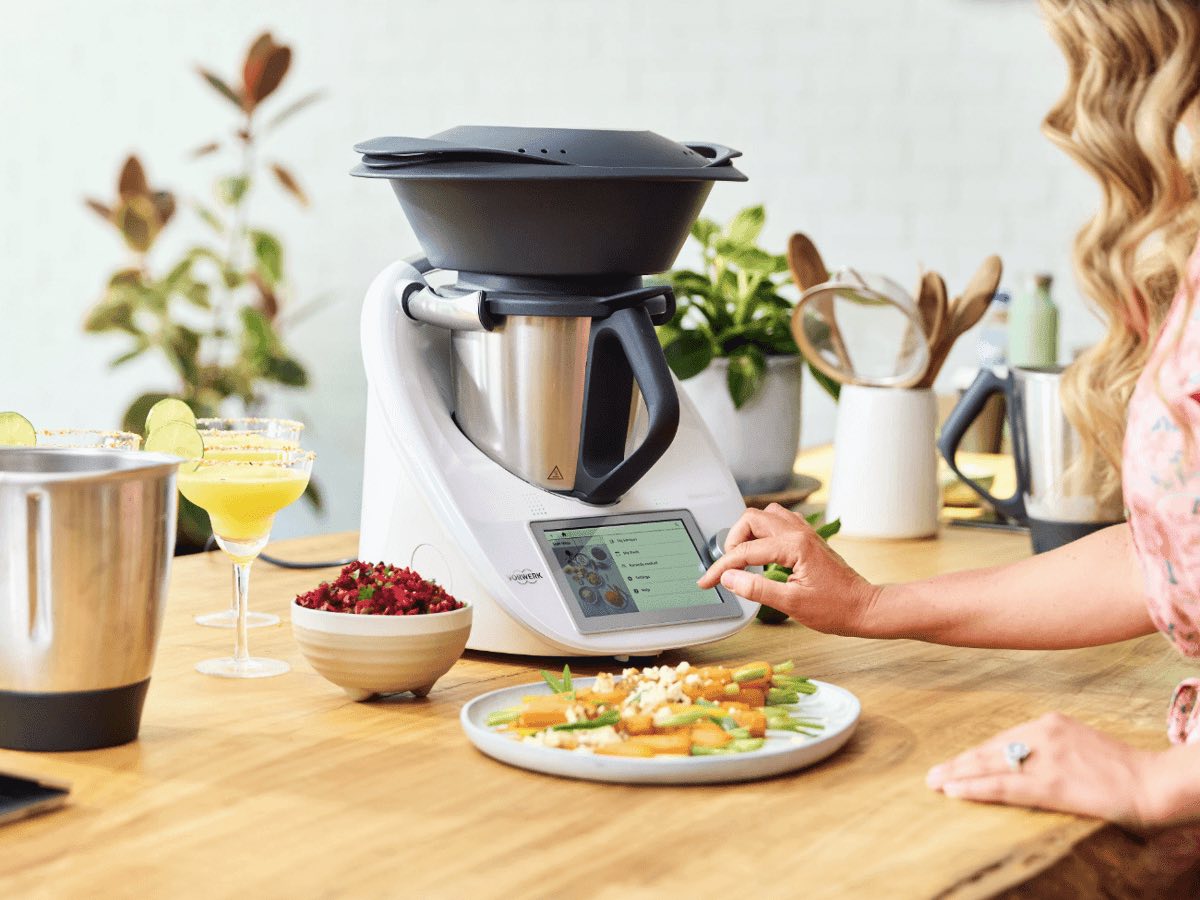 A Thermomix on a timber kitchen bench surrounded by fresh dishes